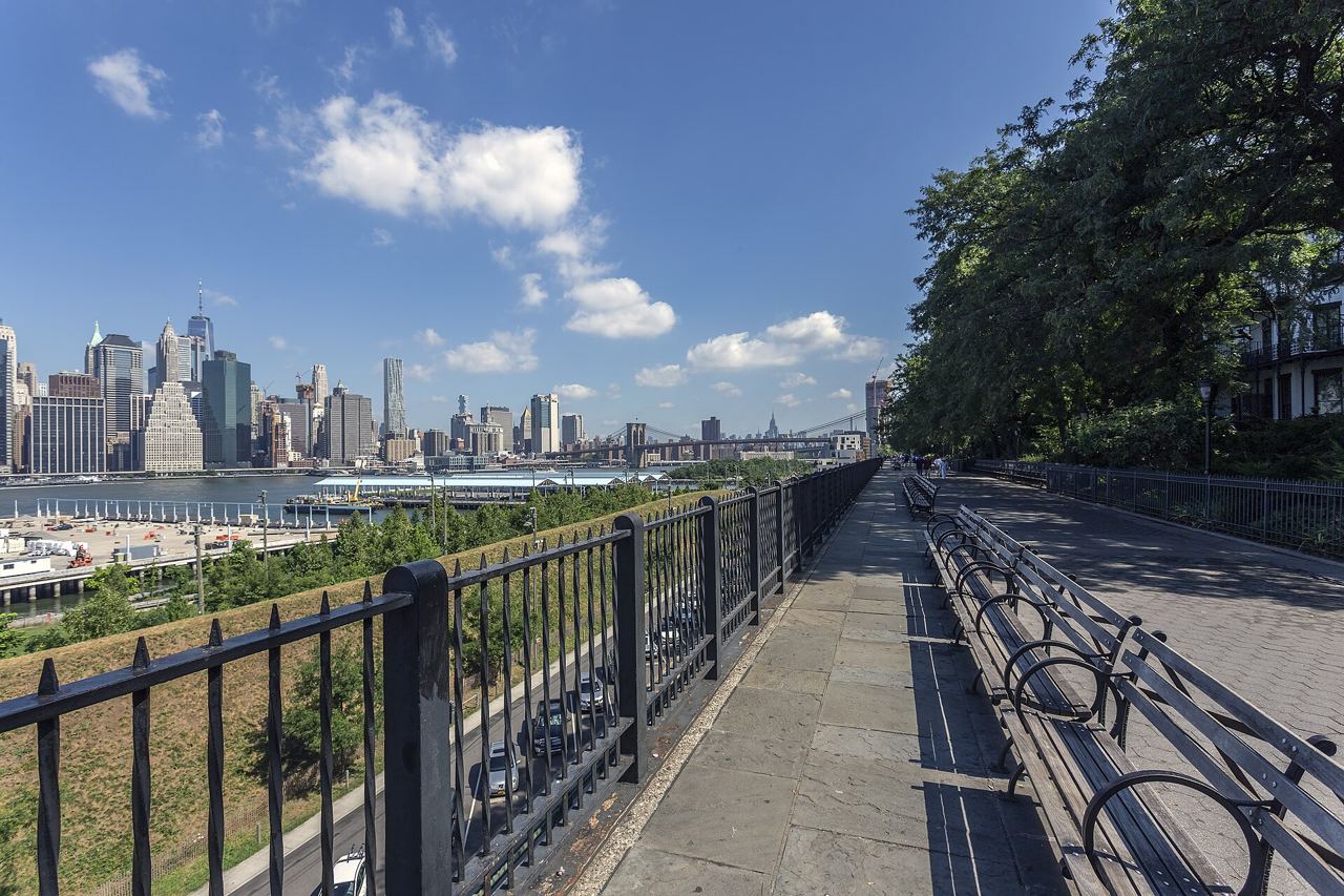 Chodník Brooklyn Heights Promenade se zábradlím, lavičkami a výhledem na Manhattan