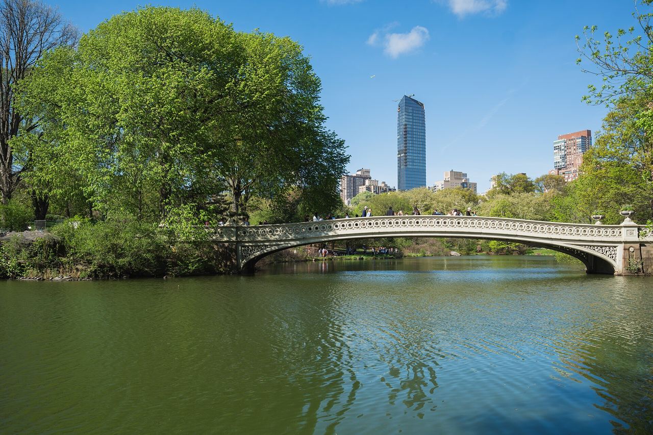 Bow Bridge v Central Parku nad jezerem, za stromy se tyčí mrakodrapy Central Park South