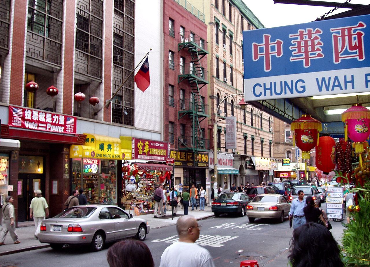 Rušná ulice v Chinatownu na Manhattanu s barevnými obchody, lampiony a požárními schodišti