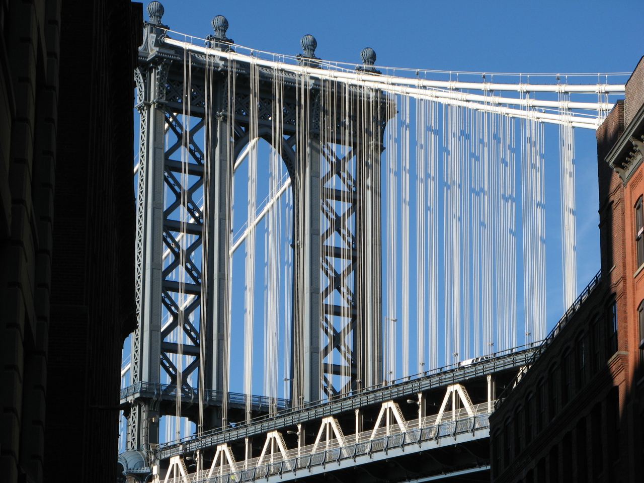 Pilíř Manhattan Bridge mezi cihlovými fasádami ve čtvrti DUMBO za slunečného dne
