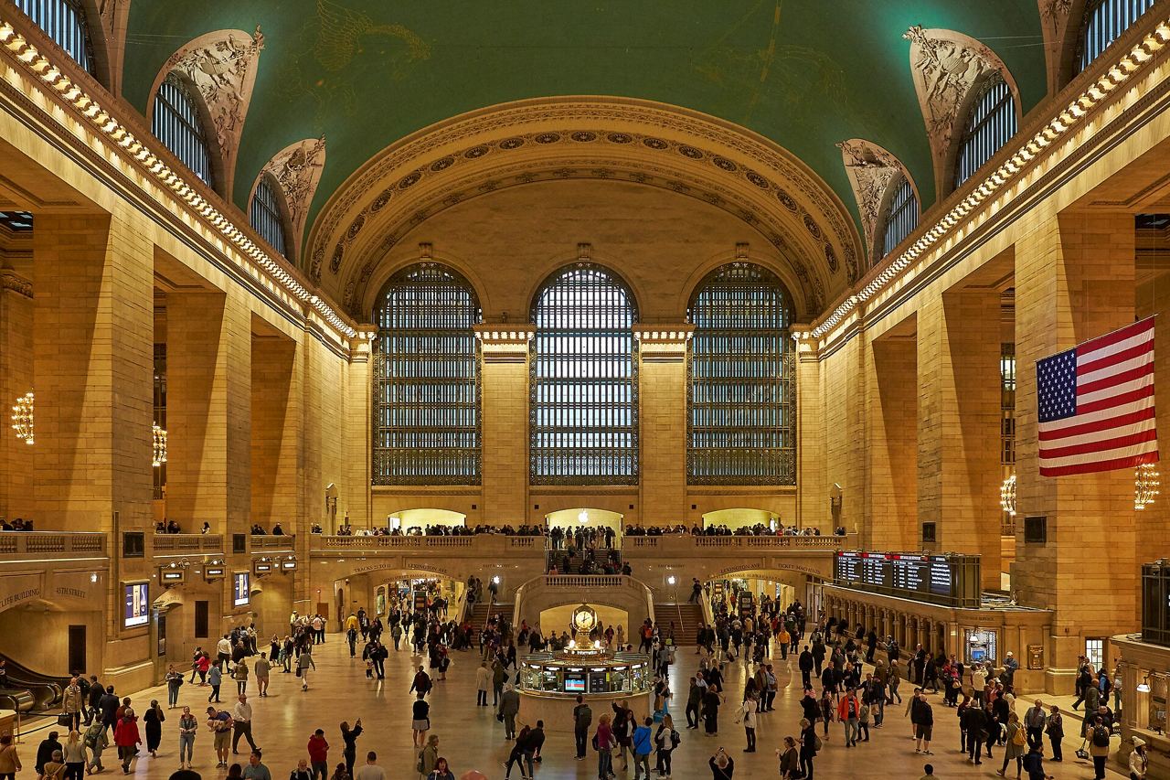 Hlavní hala Grand Central Terminal s klenutým stropem, velkými okny a proudem cestujících