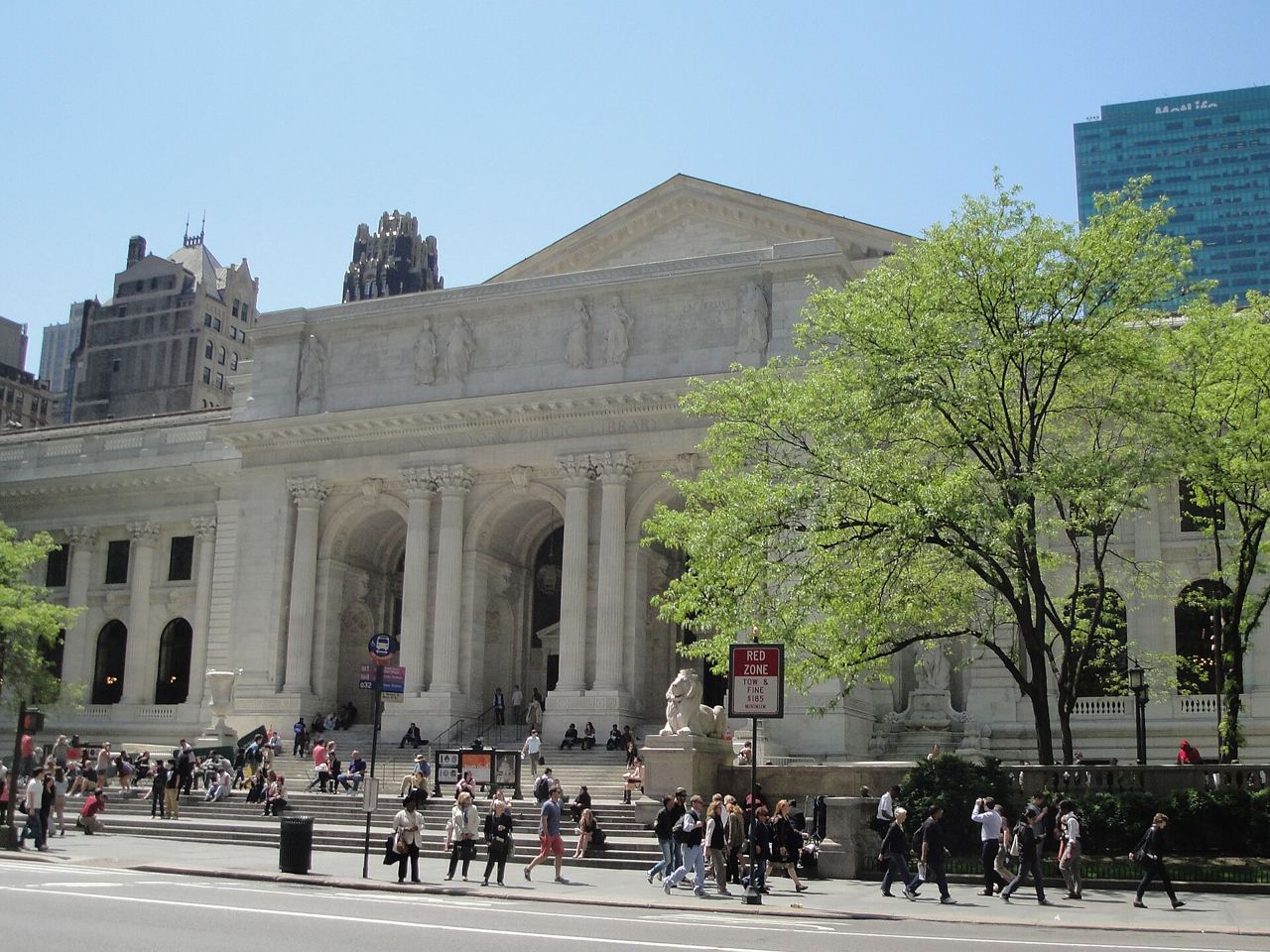 Průčelí New York Public Library na Páté avenue se schodištěm, sloupy a chodci