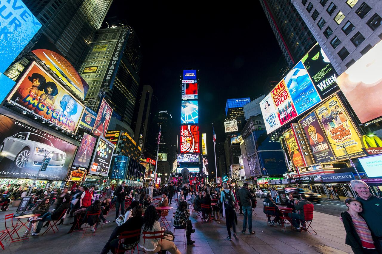 Times Square v noci s rozsvícenými obrazovkami, mrakodrapy a davy lidí na náměstí